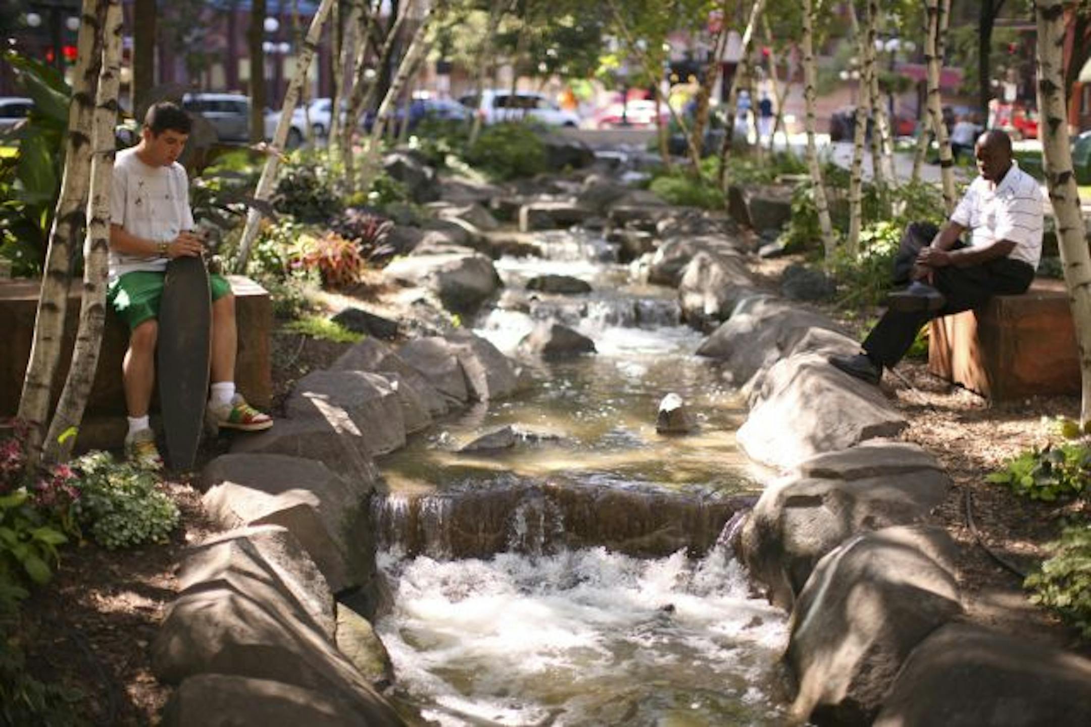 JEFF WHEELER • jwheeler@startribune.com Alex Martinez, left, of South St. Paul and James Dortch of Heron Lake were drawn to the stream running through Mears Park for some quiet contemplation Tuesday afternoon. Around the park, restaurants and live-music venues are providing downtown with a new entertainment scene.