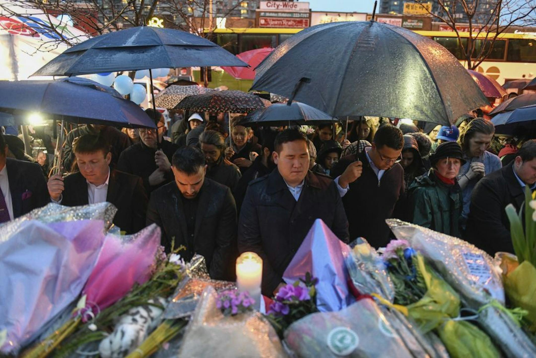 People bow their heads in silence at a vigil on Yonge Street in Toronto, Tuesday, April 24, 2018, after multiple people were killed and others injured in Monday's deadly attack in which a van struck pedestrians on a Toronto sidewalk.