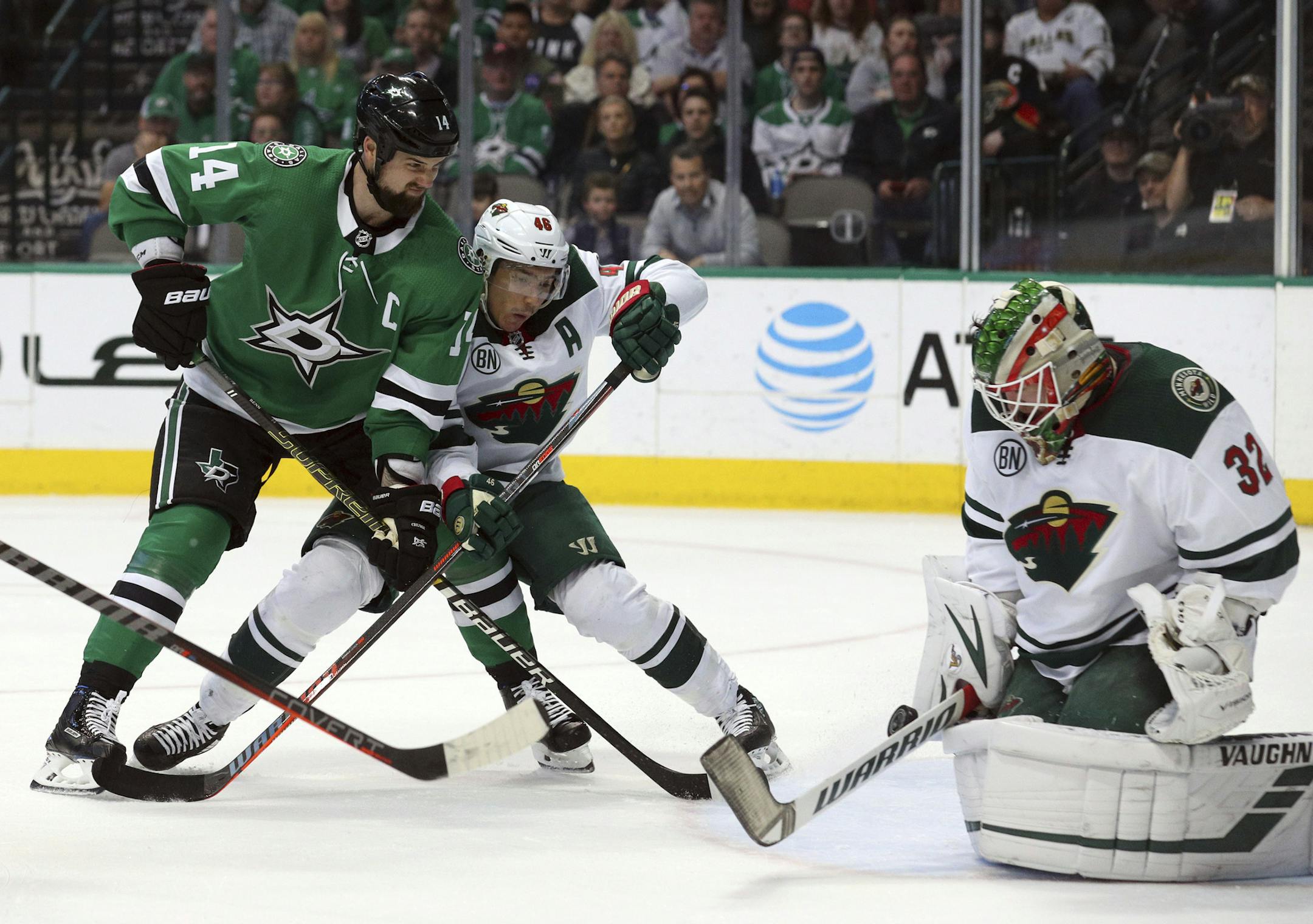 Dallas Stars left wing Jamie Benn (14) shoots against Minnesota Wild goaltender Alex Stalock (32) as defenseman Jared Spurgeon (46) guards in the first period of an NHL hockey game Saturday, April 6, 2019, in Dallas. (AP Photo/Richard W. Rodriguez)