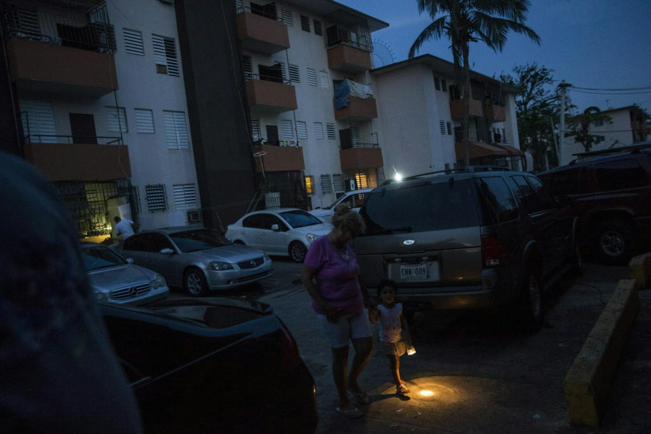 Residents of the crime-ridden Luis Lloréns Torres housing project walk in darkness after Hurricane Maria wiped out the streetlights, in San Juan, Puerto Rico, Oct. 12, 2017. Using generators, rationing and even bonfires, Puerto Ricans have had to get creative to survive weeks without power or regular water and food after Maria. (Dennis M. Rivera Pichardo/The New York Times)