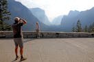 Dario Raffaelli, left, of Piza, Italy, photographs his wife, Paola Raffaelli, at Tunnel View as the Yosemite Valley reopens in Yosemite, Calif., on Tu