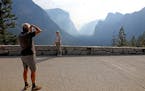 Dario Raffaelli, left, of Piza, Italy, photographs his wife, Paola Raffaelli, at Tunnel View as the Yosemite Valley reopens in Yosemite, Calif., on Tu