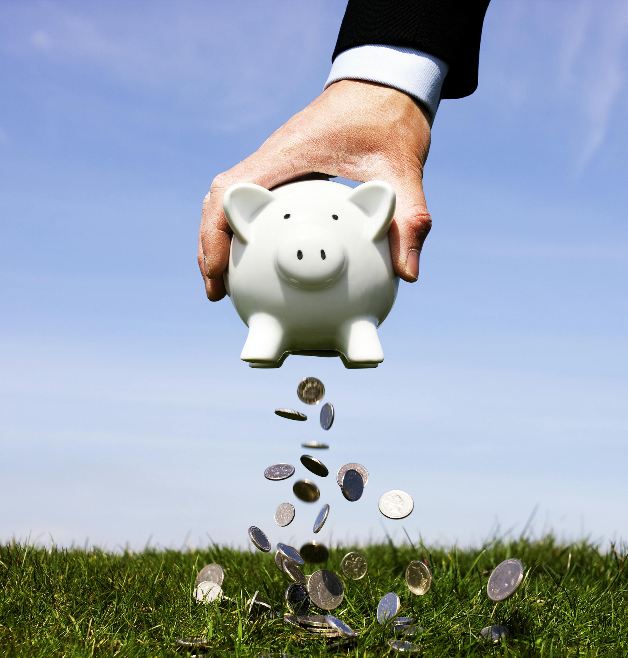 Businessman shaking money out of a piggy bank