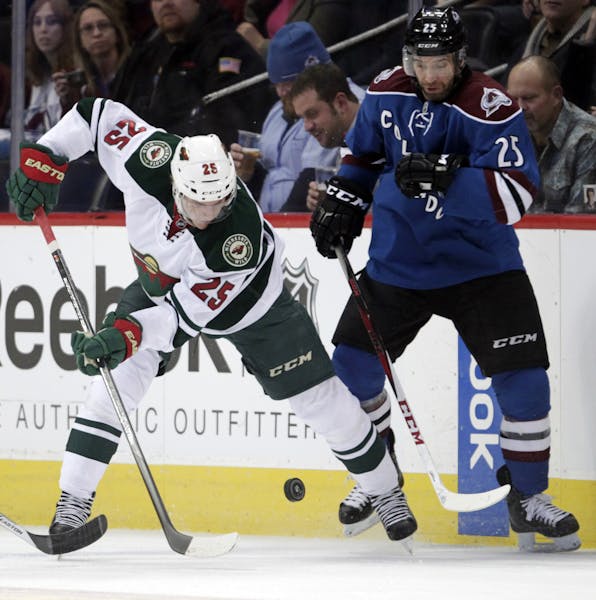 Minnesota Wild defenseman Jonas Brodin, left, tries to control the puck against Colorado Avalanche center Maxime Talbot during the first period of an 