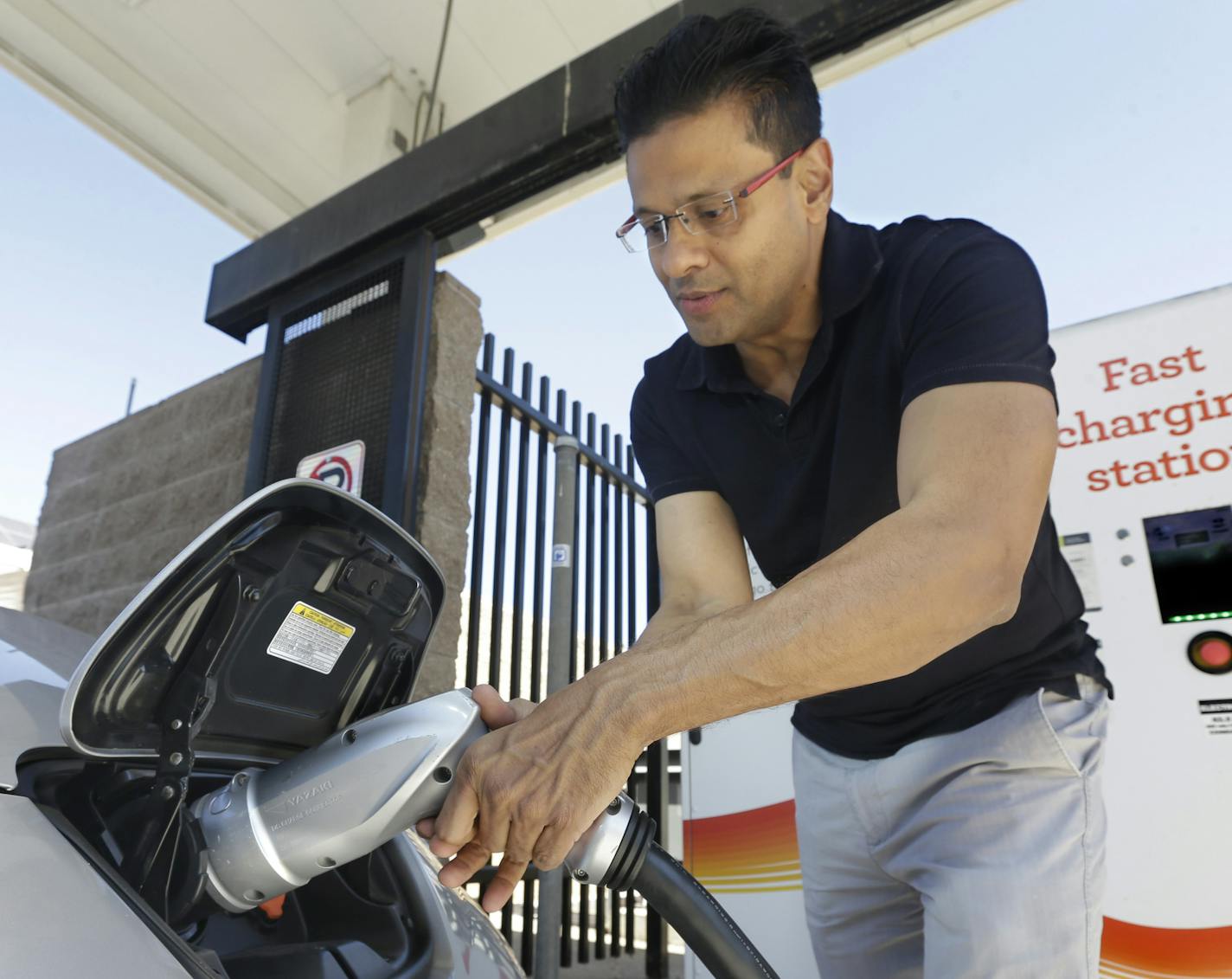 FILE - In this Thursday, Sept. 17, 2015 file photo, Darshan Brahmbhatt, plugs a charger into his electric vehicle at the Sacramento Municipal Utility District charging station in Sacramento, Calif. Calif., Gov Jerry Brown, on Friday, Jan. 26, 2018, issued and executive order outlining a plan to put 5 million zero-emission vehicles on California's roads by 2030. (AP Photo/Rich Pedroncelli, File)