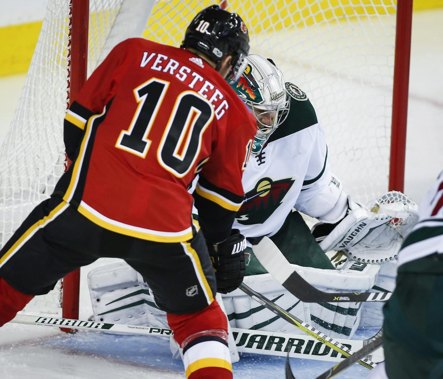 Minnesota Wild goalie Alex Stalock, right, tries to stop Calgary Flames' Kris Versteeg from scoring during the third period of an NHL hockey game Saturday, Oct. 21, 2017, in Calgary, Alberta. (Jeff McIntosh/The Canadian Press via AP)