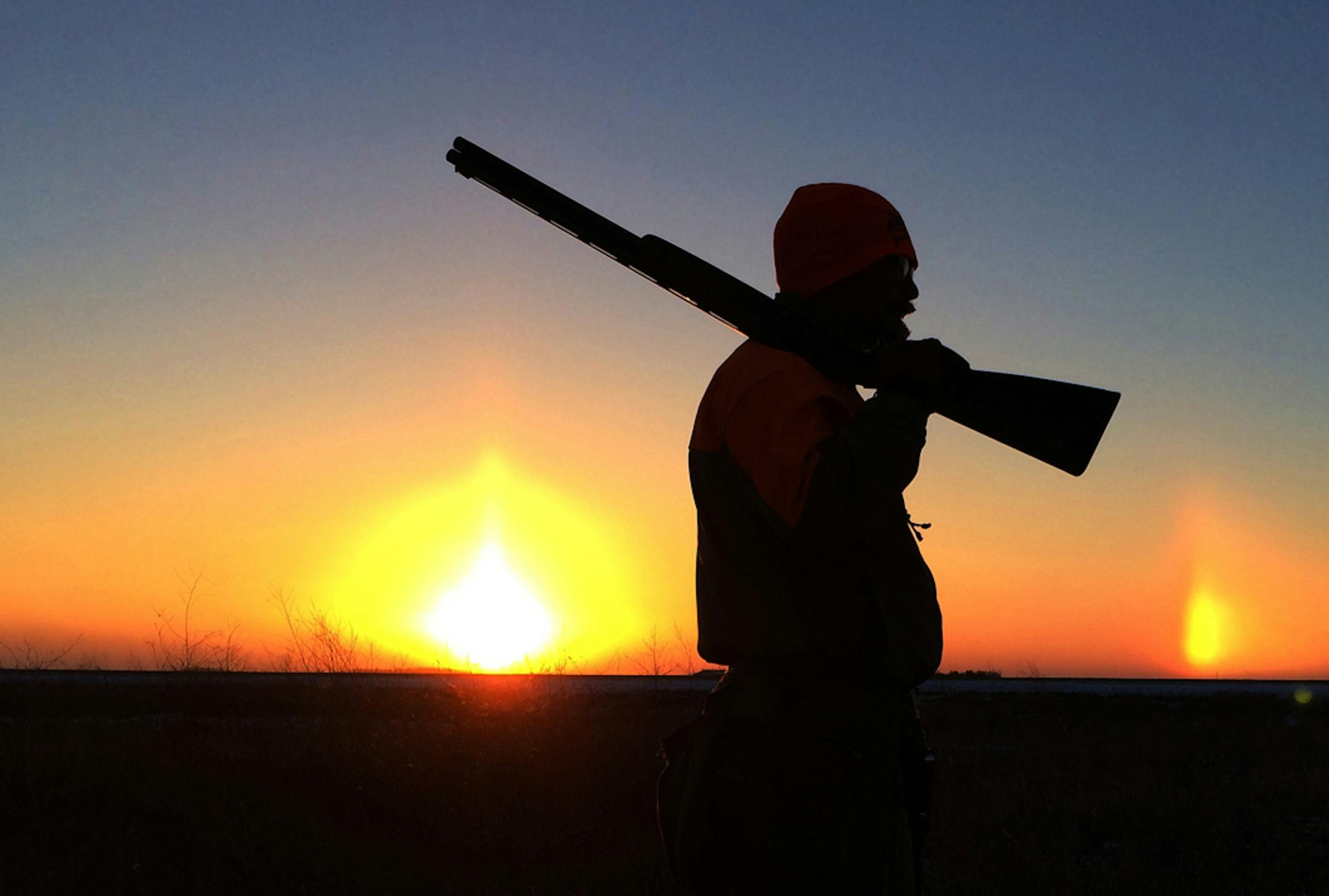 Doug Smith/Startribune; Nov. 22, 2013, near Thief River Falls; Bob St. Pierre of Hugo is bracketed by the setting sun and a sundog on a cold day recently in northwestern Minnesota while hunting sharp-tailed grouse.