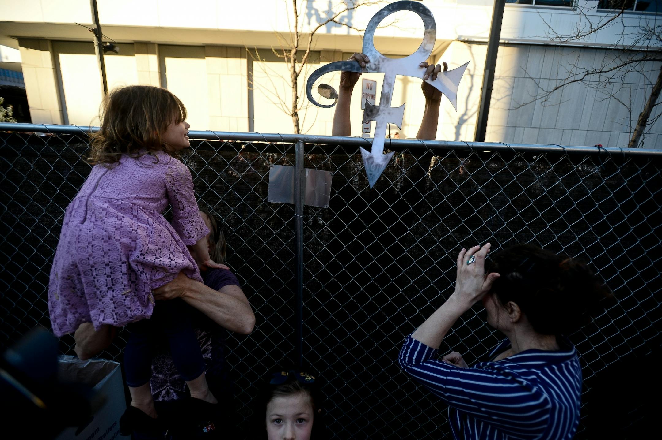 A prince fan held a Prince symbol cutout over the fence from beyond the barrier containing First Ave's Prince memorial block party Saturday.