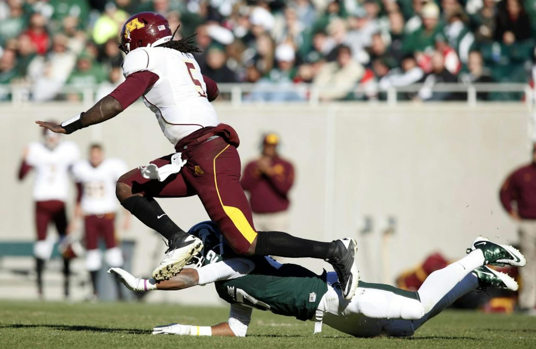 Minnesota quarterback MarQueis Gray (5) hurdles Michigan State's Kurtis Drummond, bottom, during the fourth quarter of an NCAA college football game, Saturday, Nov. 5, 2011, in East Lansing, Mich. Michigan State won 31-24.