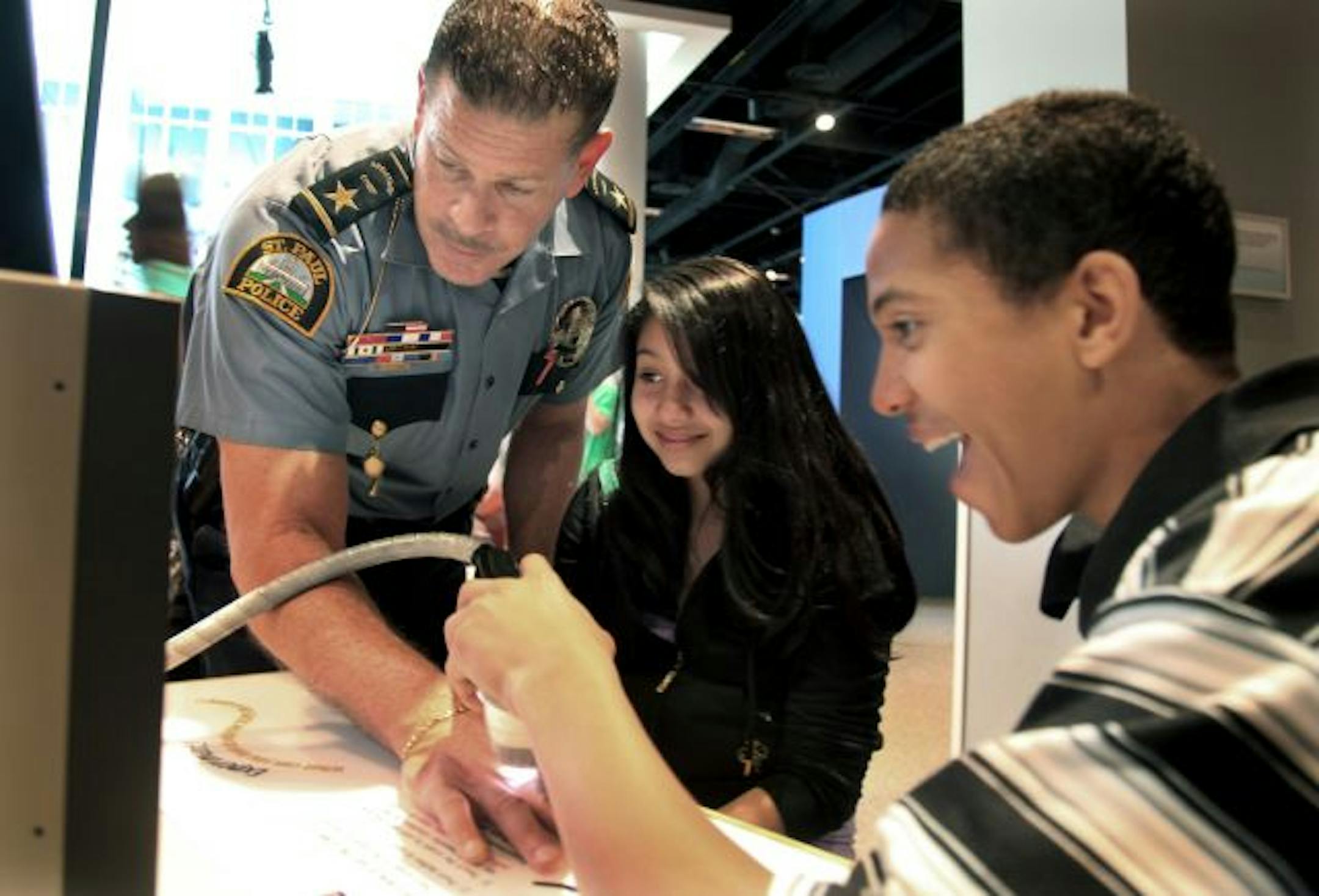 Thomas Smith, who'll soon be St. Paul's police chief, let Yesenia Garcia Franco and DeShon Simmons explore his thumbprint at the Science Museum of Minnesota. Smith, who mentors students at schools in his neighborhood, was able to arrange a visit by about 10 of them to the museum last month