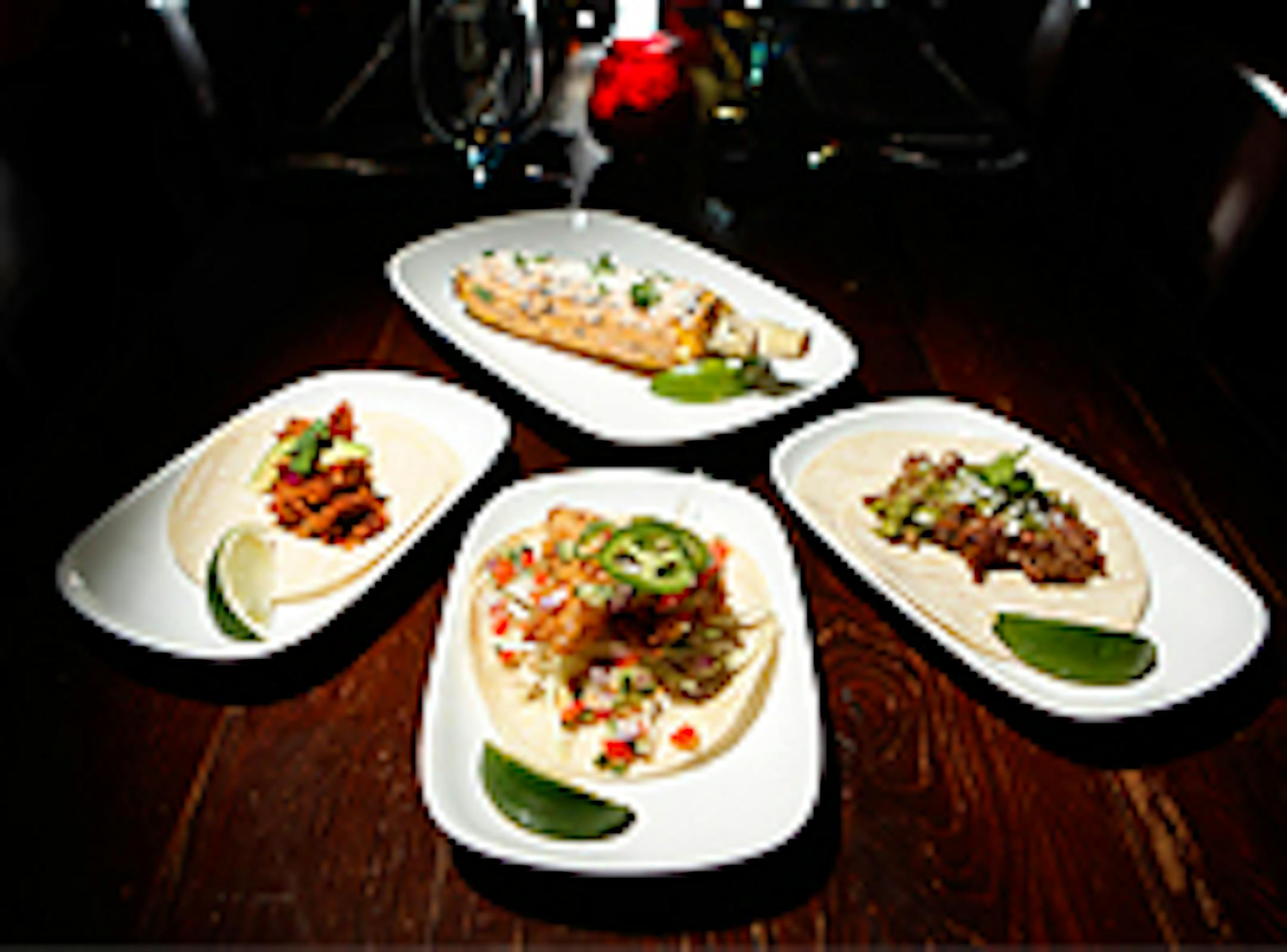 Clockwise from top - grilled corn with chipotle aioli, cotija and cilantro. Pork carnitas taco with serrano chile salsa, fried mahi-mahi taco with citrus-cucumber pico de gallo, and chicken al pastor taco with avocado and habenero-pickeled onions.