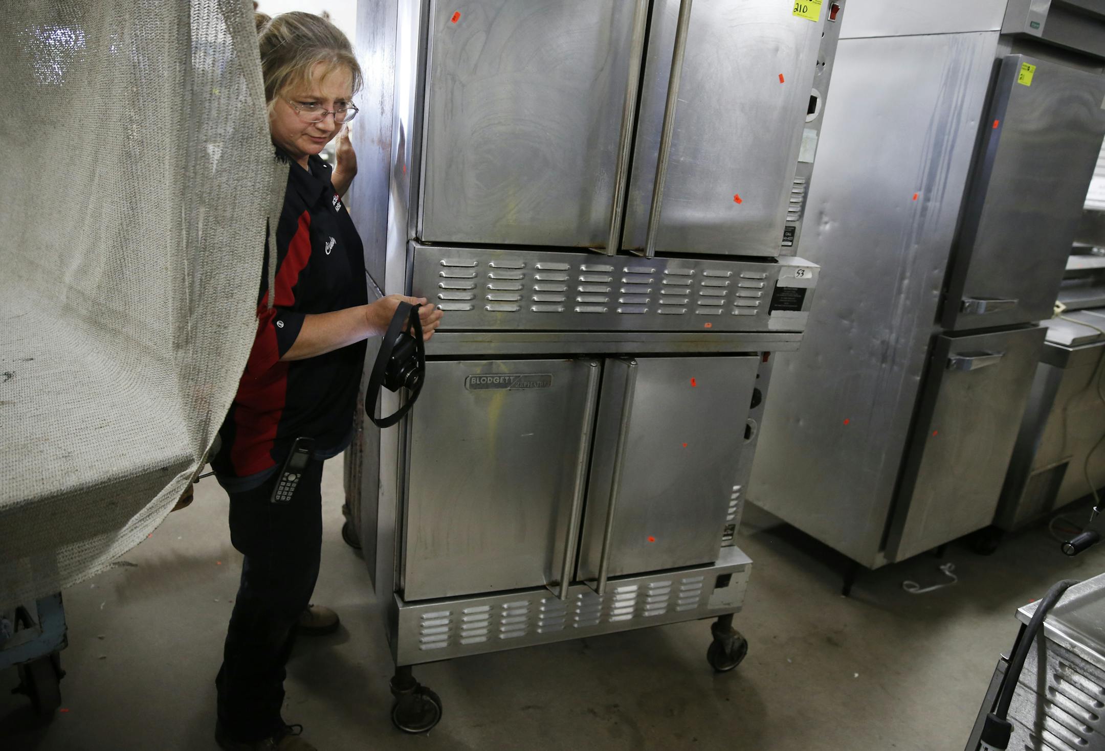 At AuctionMasters.com's warehouse which currently has mostly restaurant appliances and furniture for auction, Cindy Schummer's job is to take picture of the appliances for the upcoming auction. She has worked there for the past 20 years . ] tsong-taataarii@startribune.com
