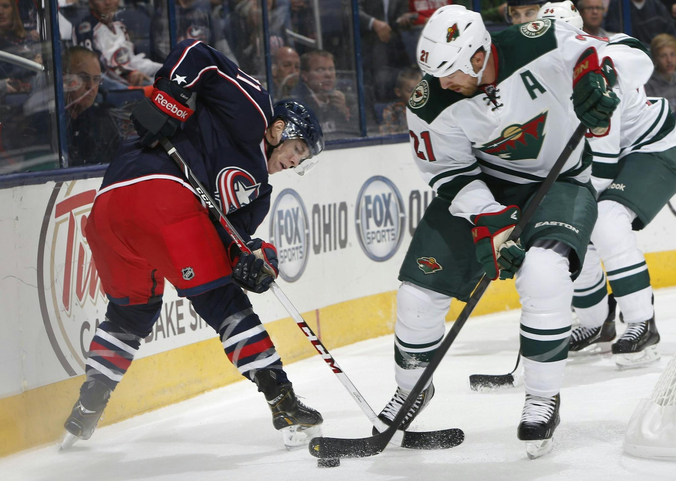 Matt Calvert (left) of the Columbus Blue Jackets is defended by the Wild's Kyle Brodziak (21) during Monday's preseason game. The Wild claimed a 2-1 shootout victory.