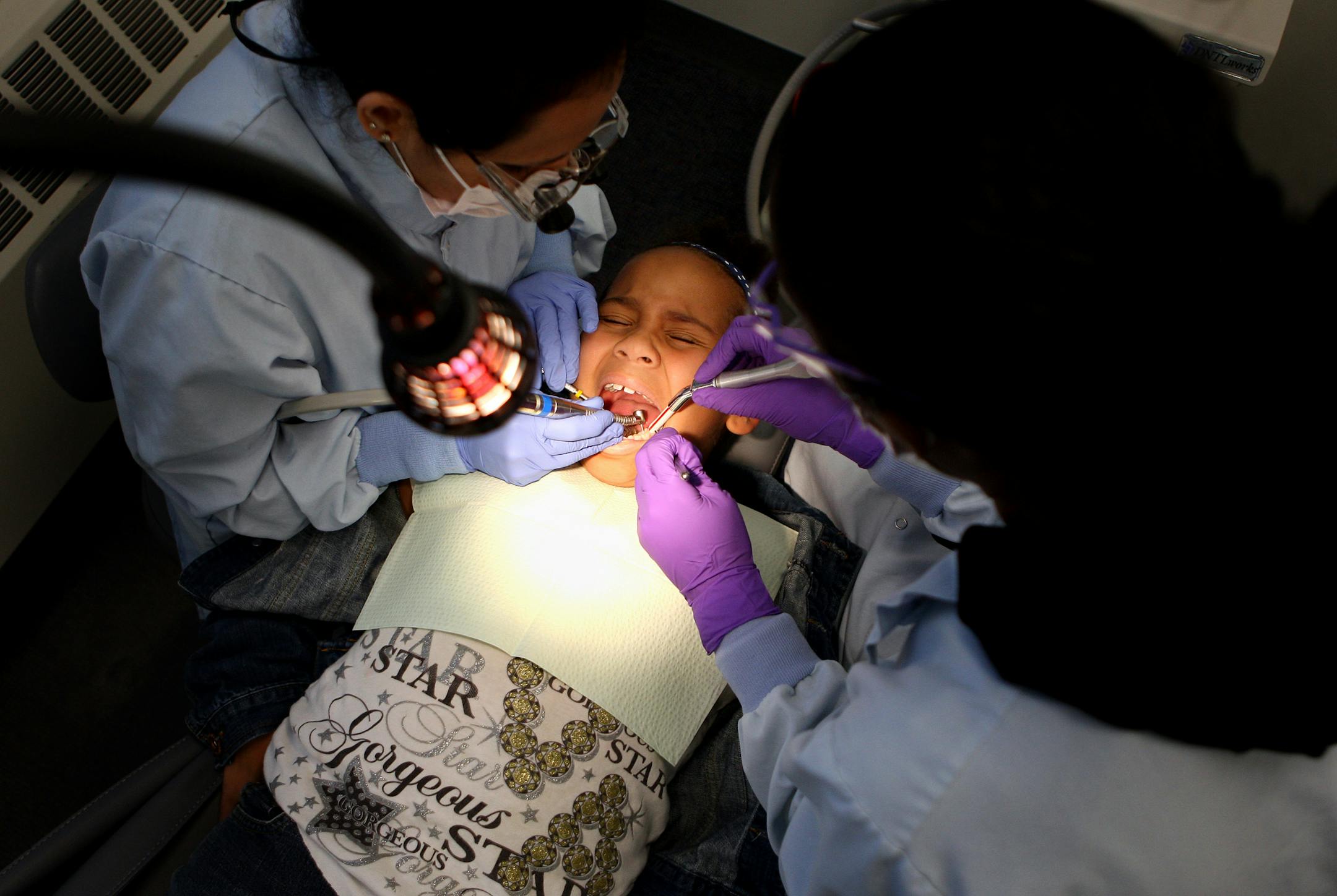 Dr. Geeta Mantri, left, and dental assistant Mewael Gebreziabher filled a tooth for 7-year-old Sabriyah Murigi in the clinic at John A. Johnson Elementary School in St. Paul on Wednesday. The city's Invest St. Paul initiative has teamed up with Smiles Across Minnesota to offer the low-cost care.