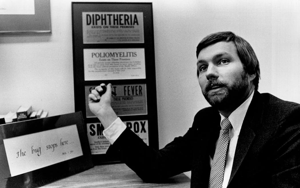 February 16, 1986 State Epidemiologist Michael Osterholm says quarantine of people carrying AIDS virus is not the answer; 1930s-era quarantine signs for other diseases are on his office wall. February 7, 1986 