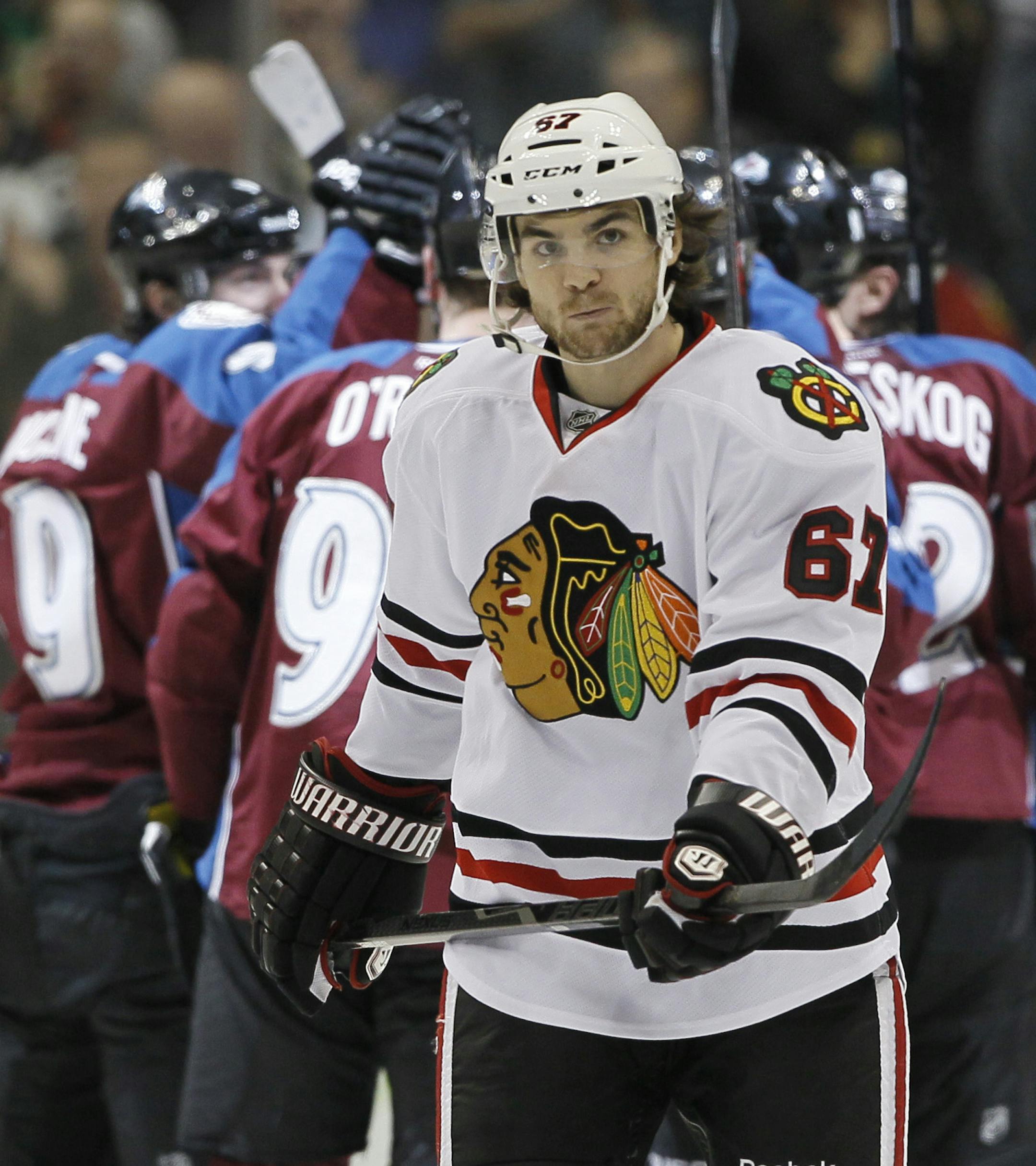 As members of the Colorado Avalanche, back, celebrate a goal by Ryan O'Reilly, Chicago Blackhawks right wing Michael Frolik (67), of the Czech Republic, skates back to the bench in the second period of an NHL hockey game in Denver, Friday, March 8, 2013. (AP Photo/David Zalubowski)