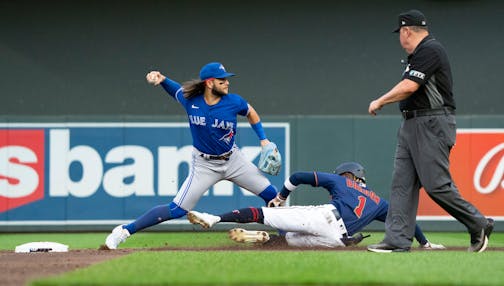 Toronto Blue Jays shortstop Bo Bichette (11) works on completing a double play as Minnesota Twins left fielder Nick Gordon (1) tries to slide into second in the second inning.