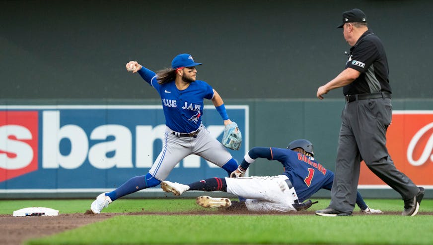 Toronto Blue Jays shortstop Bo Bichette (11) works on completing a double play as Minnesota Twins left fielder Nick Gordon (1) tries to slide into second in the second inning.