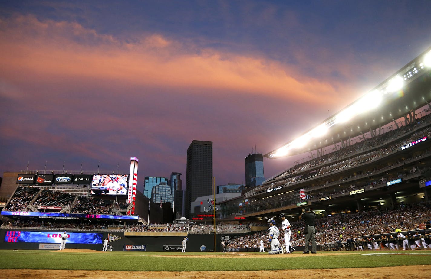 The setting sun reflects on storm clouds over the Minneapolis skyline and Target field as Minnesota Twins&#xed; Eddie Rosario comes to bat in a baseball game against the Kansas City Royals, Tuesday, June 9, 2015, in Minneapolis. (AP Photo/Jim Mone)