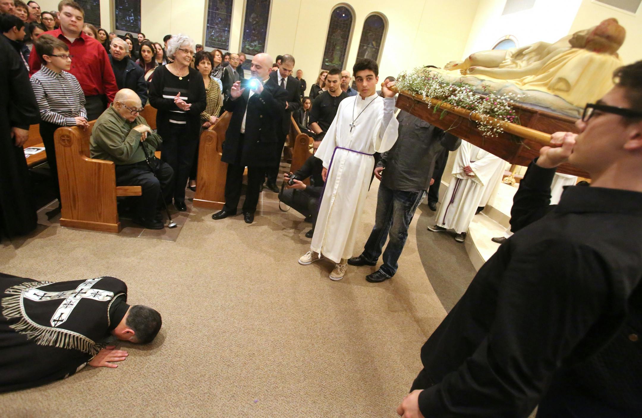 Pastor Sharbel-Ghattas Maroun prostrates himself before the shroud of the body of Jesus during a Good Friday service Friday, March 26, 2016, at St. Maron's Catholic Church in Minneapolis.