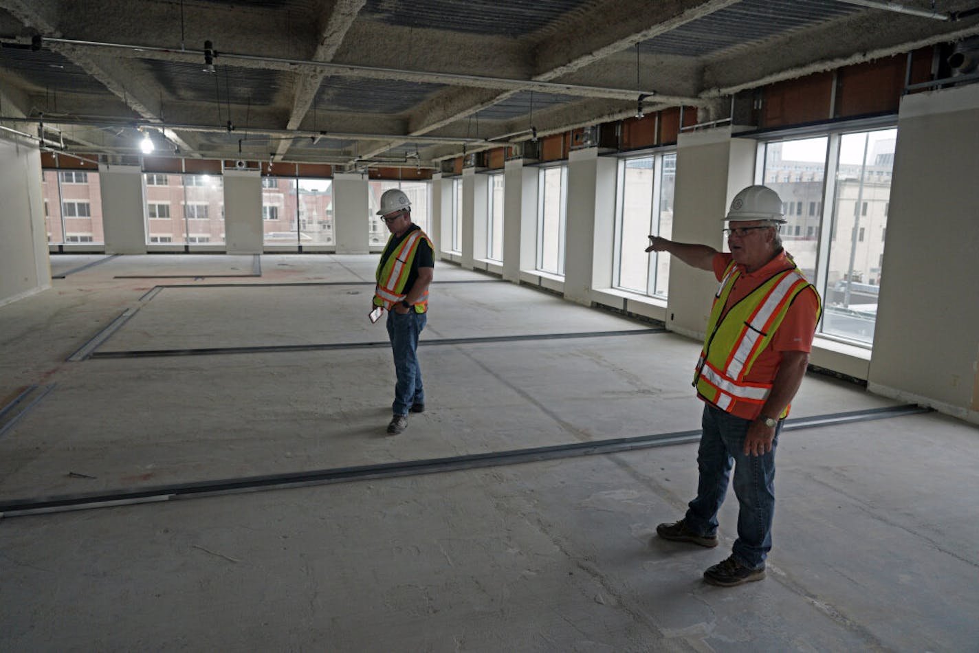 Construction manager Ron Basara, right, shows off the outline of studio apartments going in at the former Ecolab University Center in downtown St. Paul.