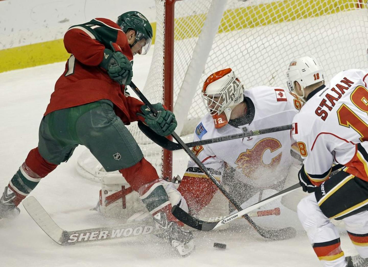 Minnesota Wild's Zach Parise, left, is thwarted in his attempt to score by Calgary Flames goalie Reto Berra in the first period of an NHL hockey game, Tuesday, Nov. 5, 2013, in St. Paul, Minn.