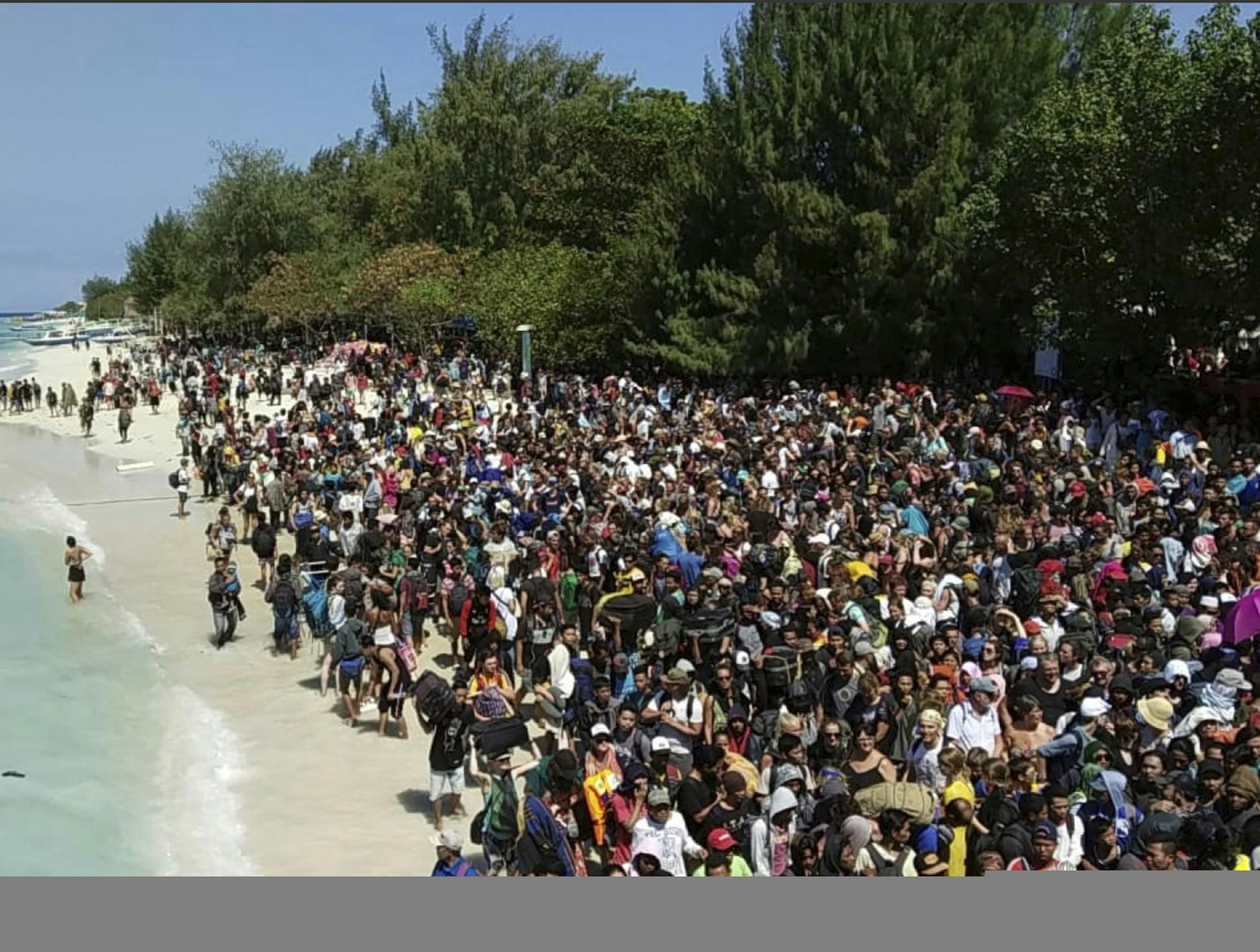 In this photo released by the Indonesian Marine Police, tourists affected by a strong earthquake line up on a beach as they wait to be evacuated on Gili Trawangan Island, Indonesia, Monday, Aug. 6, 2018. Indonesian authorities said Monday that rescuers still haven't reached some devastated parts of the tourist island of Lombok after a powerful earthquake flattened houses and toppled bridges, killing a number of people and shaking neighboring Bali. The death toll is expected to rise. (AKBP. Dewa