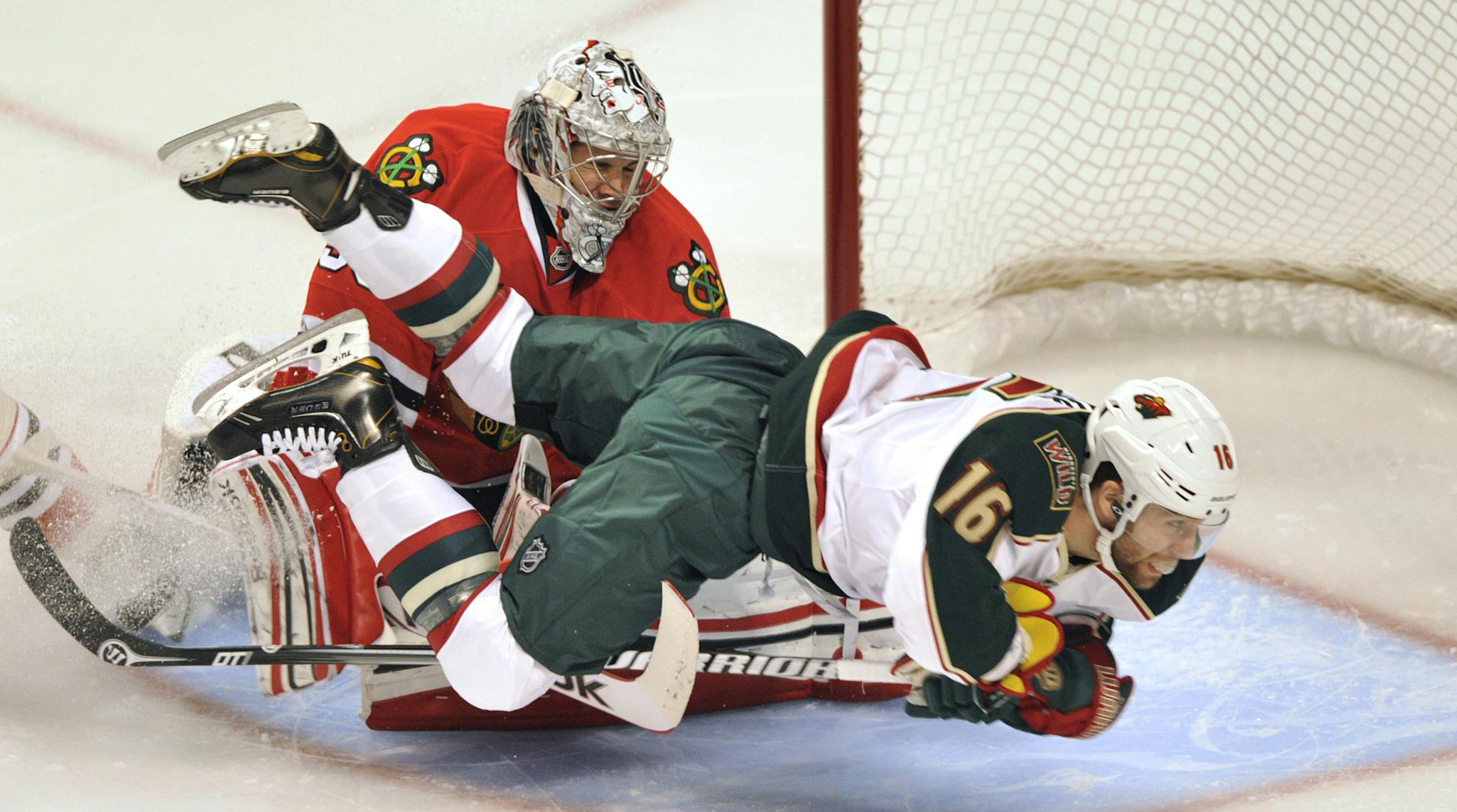 Minnesota Wild's Jason Zucker (16) collides with Chicago Blackhawks' Corey Crawford during the first period of Game 1 of an NHL hockey Stanley Cup playoff series, Tuesday, April 30, 2013, in Chicago. (AP Photo/Jim Prisching)