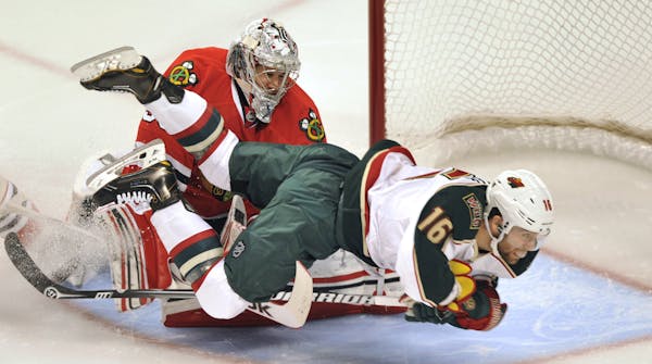 Minnesota Wild's Jason Zucker (16) collides with Chicago Blackhawks' Corey Crawford during the first period of Game 1 of an NHL hockey Stanley Cup pla