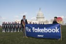 IMAGE DISTRIBUTED FOR AVAAZ - Avaaz campaigners hold a banner in front of 100 cardboard cutouts of the Facebook founder and CEO stand outside the U.S.