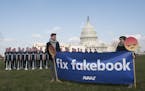 IMAGE DISTRIBUTED FOR AVAAZ - Avaaz campaigners hold a banner in front of 100 cardboard cutouts of the Facebook founder and CEO stand outside the U.S.