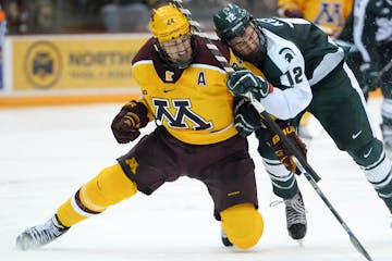 Minnesota Golden Gophers right wing Hudson Fasching (24) and Michigan State Spartans forward Ryan Keller (12) collided while chasing down the puck in 