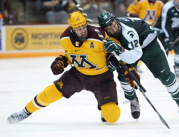Minnesota Golden Gophers right wing Hudson Fasching (24) and Michigan State Spartans forward Ryan Keller (12) collided while chasing down the puck in 