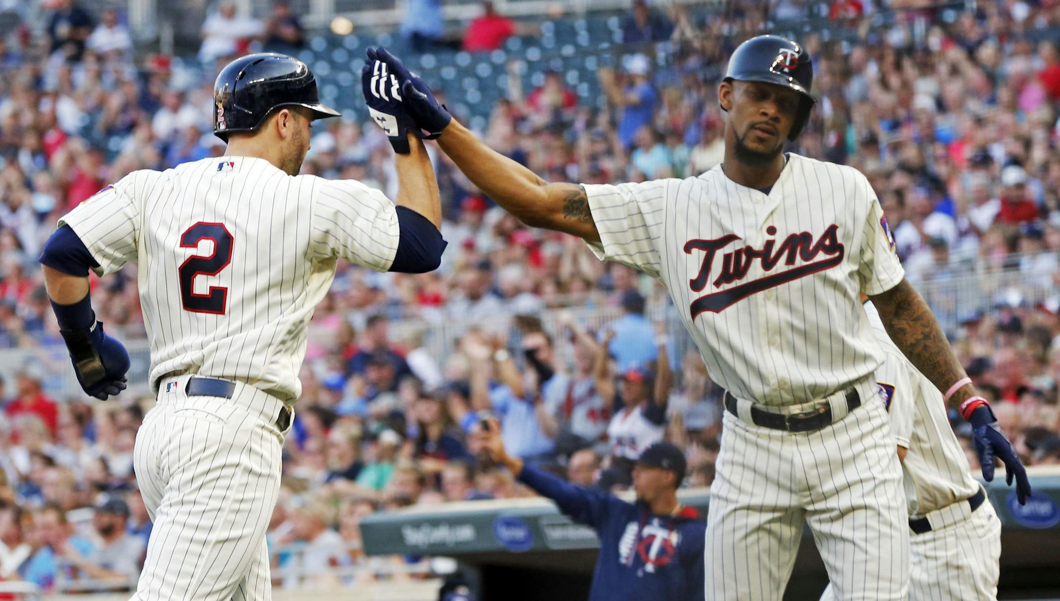 Minnesota Twins' Byron Buxton, right, congratulates Brian Dozier as he scores on a double by Joe Mauer off Kansas City Royals pitcher Onelki Garcia in the first inning of a baseball game Saturday, Sept, 2, 2017, in Minneapolis. (AP Photo/Jim Mone)
