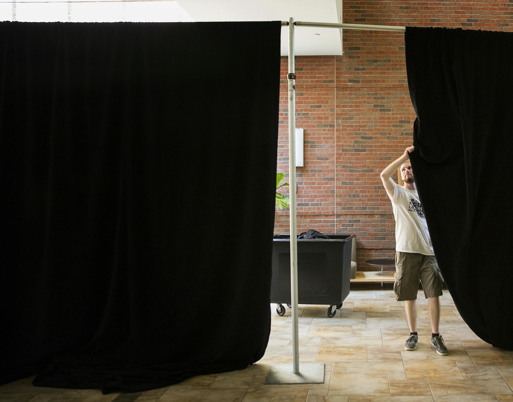 Jack Swift set up curtains for the polling place at the Oren Gateway Building at Augsburg College before Tuesday's primary election.
