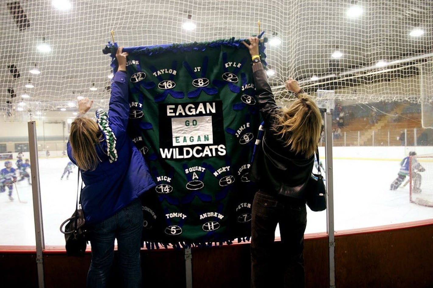 JEFFREY THOMPSON � jthompson@startribune.com Fargo, ND - Feb. 22, 2007 - Eagan squirt hockey. Eagan player moms Jodi Richmond, left, and Lisa Karel hang a banner at the Fargo Coliseum before the Wildcats first game of the tournament in Fargo, Friday, Feb. 23, 2007. GENERAL INFORMATION: Feature about youth hockey tournament culture--what traveling is like, how parents behave in the hotels, how kids spend most of their weekends in the winter, etc. // Fargo Flyers International Squirt Hockey Tourna