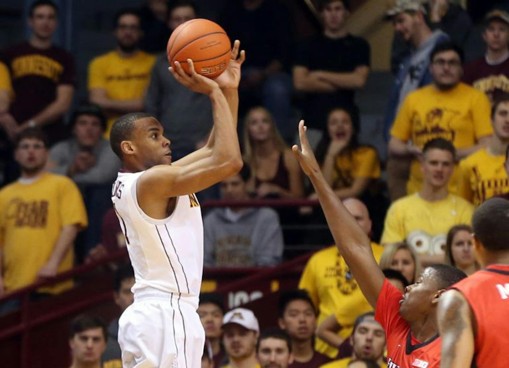 Minnesota's Andre Hollins, left, shoots as Rutgers' Junior Etou, of Congo, defends during the first half of an NCAA college basketball game, Saturday, Jan. 17, 2015, in Minneapolis.