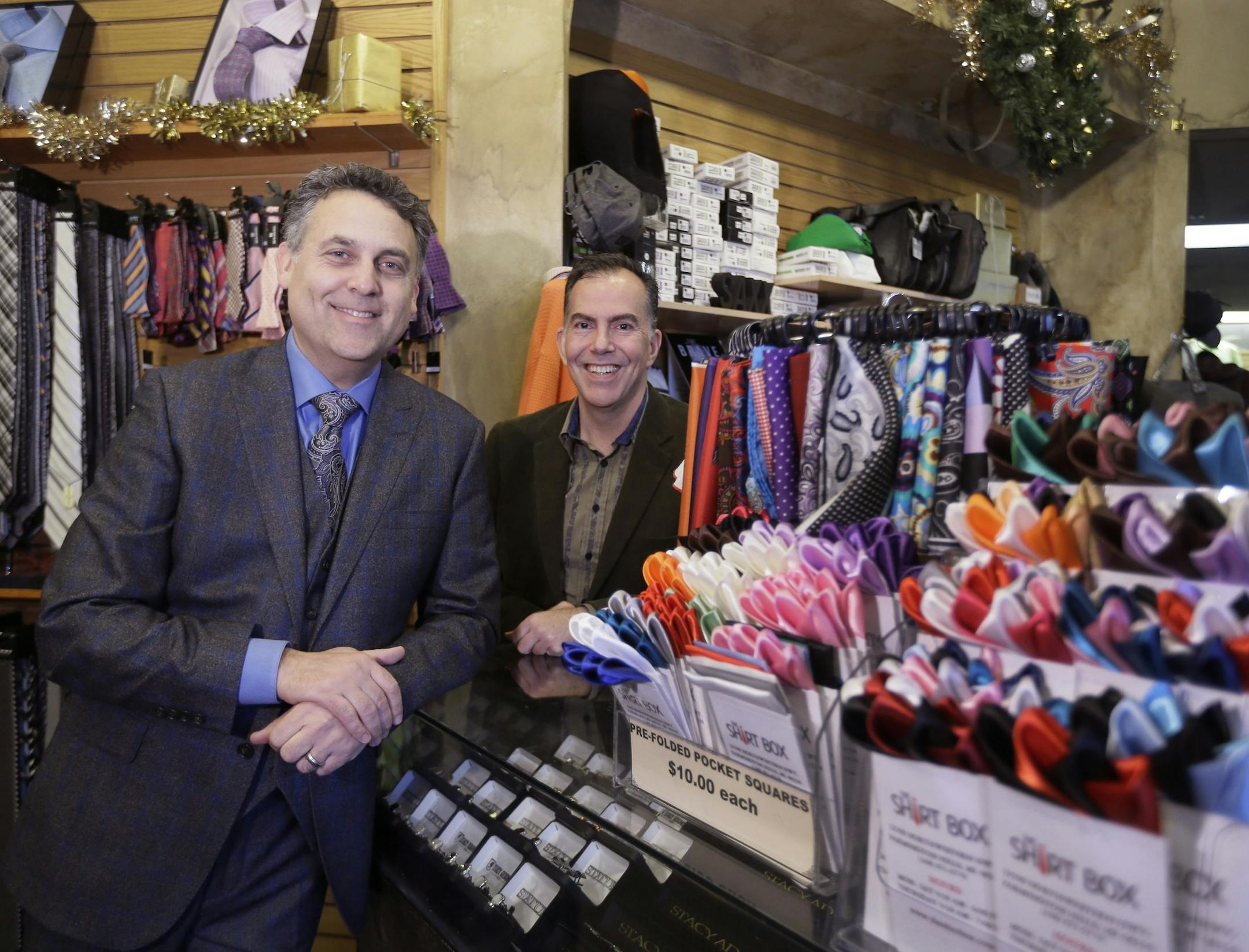 Rod Brown, left, and Ron Elkus, co-owners of The Shirt Box, pose for a photo in their store, Thursday, Dec. 3, 2015, in Farmington Hills, Mich. With the start of the holiday shopping season behind them and the big final push still to come, independent retailers have to get creative to bring customers in. The menís clothing store is holding events like bourbon tastings and giving lessons on tying bow ties on weekends during the holiday season. (AP Photo/Carlos Osorio) ORG XMIT: MICO201