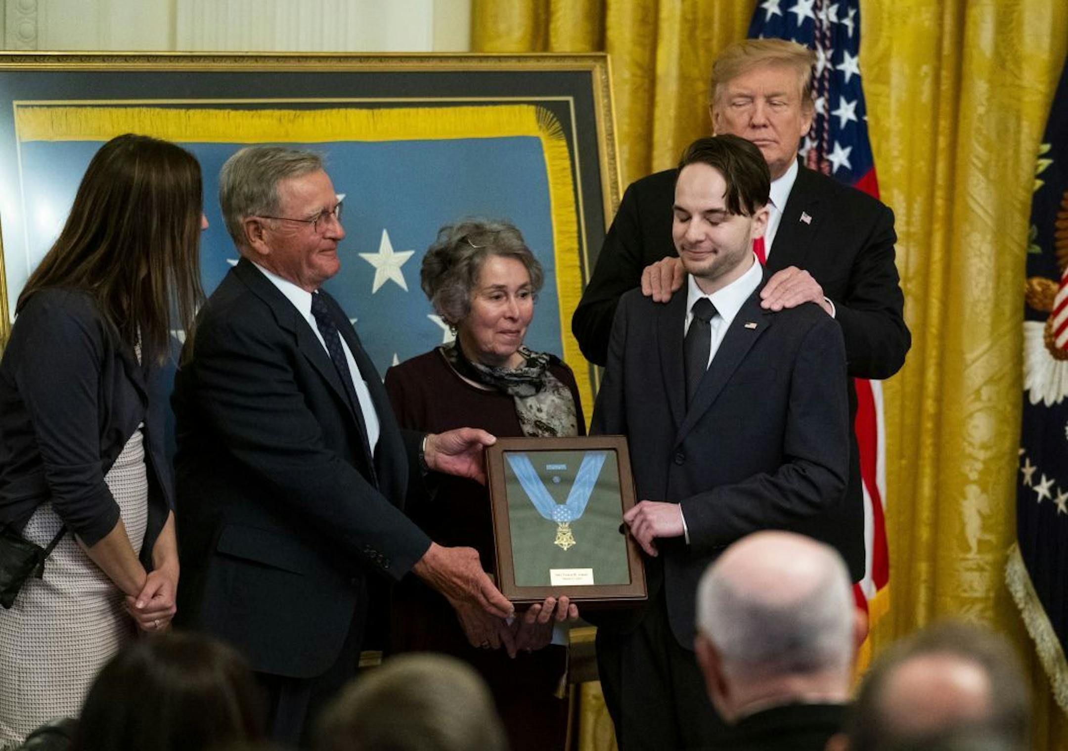 President Donald Trump stands with the family members of Army Staff Sgt. Travis Atkins, during a posthumous Medal of Honor ceremony, at the White House in Washington, March 27, 2019. At right is Atkins' son, Trevor Oliver.