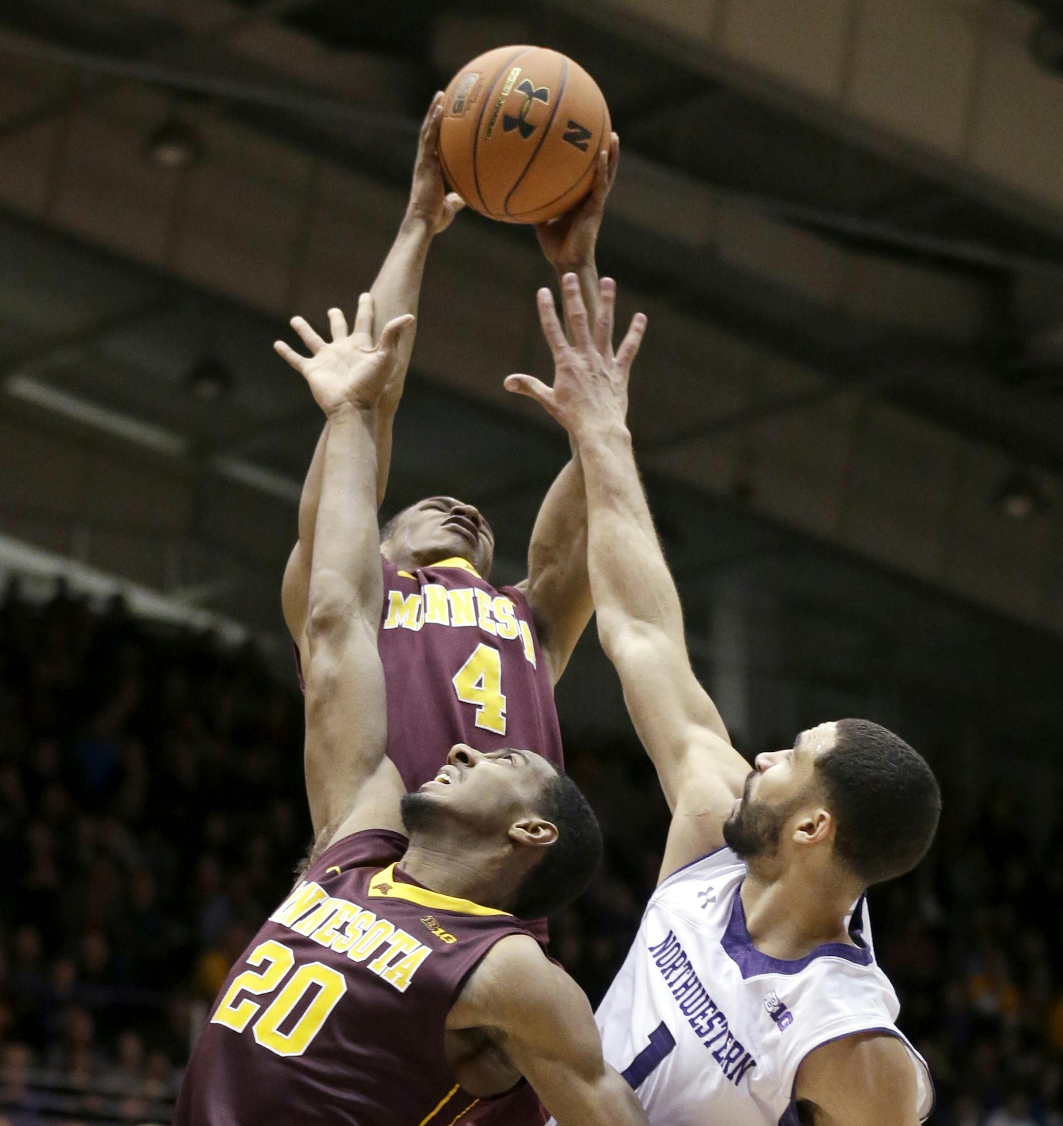 Minnesota guard DeAndre Mathieu (4) rebounds the ball against guard Austin Hollins (20) and Northwestern guard Drew Crawford (1) during the second half of an NCAA college basketball game in Evanston, Ill., Sunday, Feb. 16, 2014. Minnesota won 54-48. (AP Photo/Nam Y. Huh)