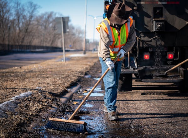 Street service worker Bradley Therres smooths asphalt over a pothole on Shepard Road in St. Paul earlier this year. 