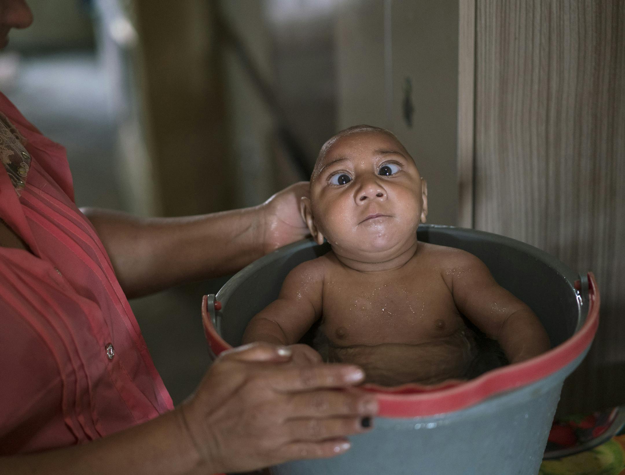 In the Jan. 30, 2016 photo, Solange Ferreira bathes her son Jose Wesley in a bucket at their house in Bonito, Pernambuco state, Brazil, Saturday. Jose who suffers from microcephaly and cries incessantly, is only calm when he is put in the bucket of water. A trick his mother learned from a nurse at a hospital. (AP Photo/Felipe Dana)