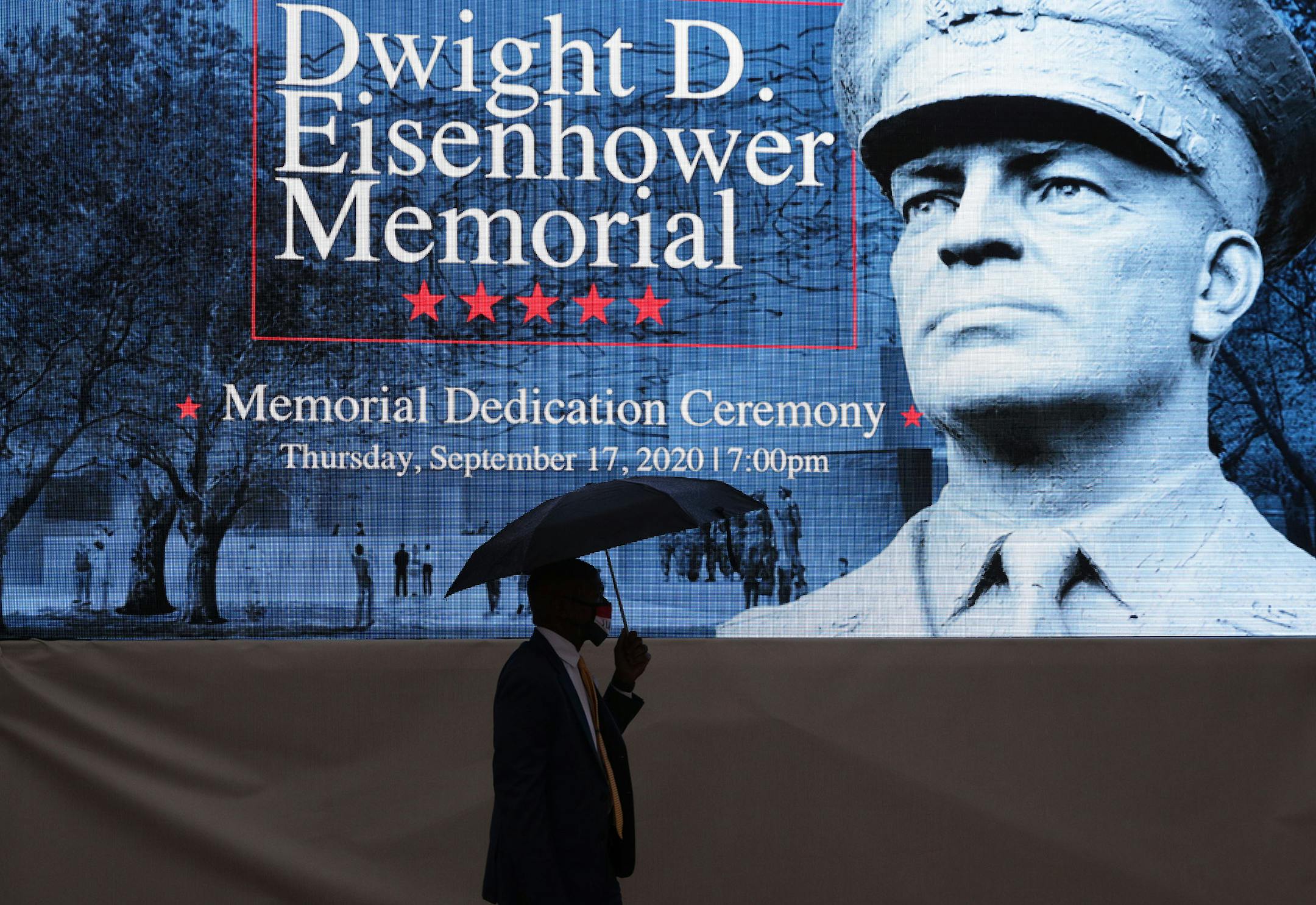 A man holds an umbrella as he passes in front of a screen prior to a dedication ceremony for The Dwight D. Eisenhower Memorial on September 17, 2020, in Washington, D.C. The memorial, commissioned by Congress in 1999, honors the legacy of the former president and World War II supreme allied commander. (Alex Wong/Getty Images/TNS) ORG XMIT: 1773666