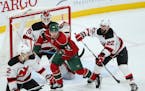 Minnesota Wild center Mikael Granlund (64) is shoved by New Jersey Devils defenseman Kyle Quincey (22) as he screens goalie Cory Schneider just as an 