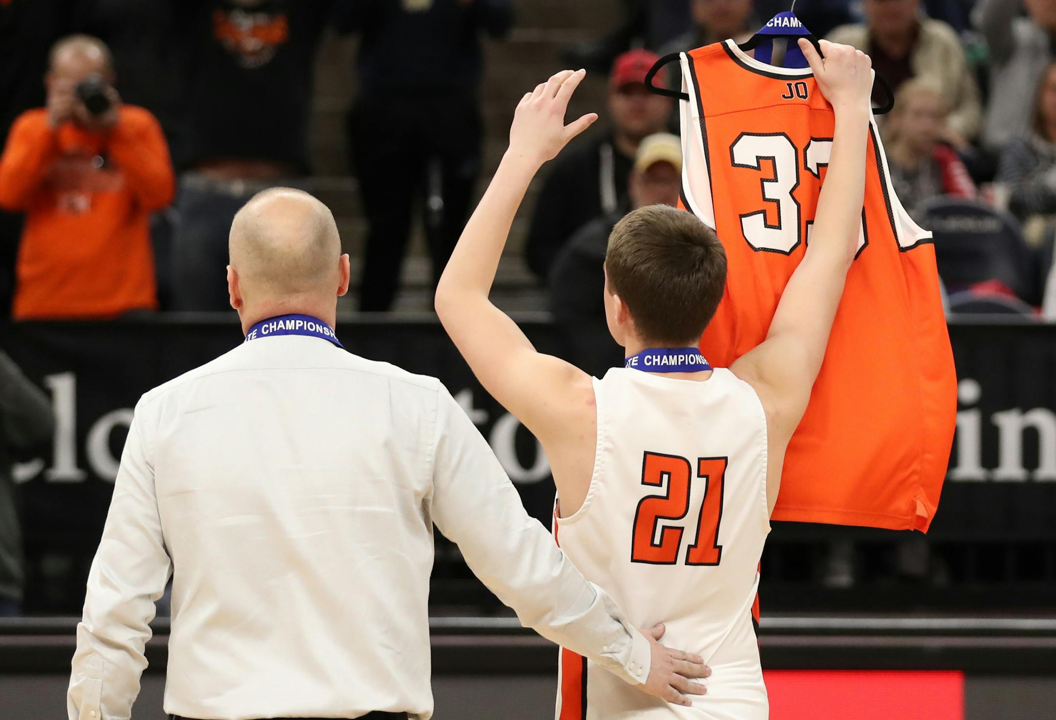 Henning guard Dylan Trana (21) held up the jersey of his teammate Jacob Quam who was killed in a car accident in 2017. Henning head coach Randy Misegades and Trana walked the jersey up to get individual medals, hanging a medal on the hanger for Quam, who would have been a senior/starter on the team this year. ] Shari L. Gross ¥ shari.gross@startribune.com Henning defeated North Woods 67-42 to win the Class 1A state boys' basketball tournament at Target Center in Minneapolis, Minn. on Saturd