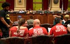 In this 2017 file photo, supporters of a $15 Minneapolis minimum wage confer as a Minneapolis City Council committee considers the issue.