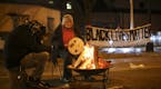 People warm themselves as they demonstrate since the Nov. 10 shooting of 24-year-old Jamar Clark, in front of the Minneapolis Police 4th Precinct on T