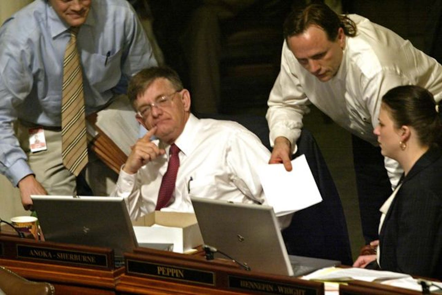 Legislators Tom Hackbarth, seated left, Jim Abeler, standing and Joyce Peppin discuss the merits of bills before the House.