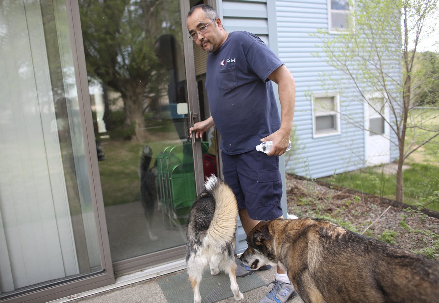 Richard Parkos lets his dogs Brutus and Jewel in from he backyard into the house he has lived in for 11 years in Ramsey, Min., Thursday, May 16, 2013. Parkos was able to get an appeal that allowed him to have a mortgage he can afford. Parkos who was in danger of foreclosure was worry about his beloved dogs Brutus and Jewel (not pictured) who have only known this house. ] (KYNDELL HARKNESS/STAR TRIBUNE) kyndell.harkness@startribune.com