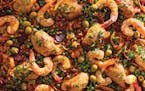 A pan of Oven Paella with Chicken, Chorizo, Shrimp, rice, and vegetables from “Hot Sheet” by Olga Massov and Sanaë Lemoine.